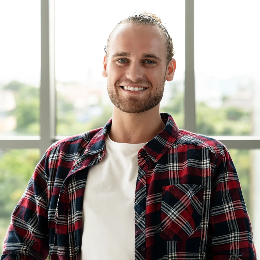 Getting-Help-Should-Be-Easy-and-Accessible-At-Changes-Healing-Center Smiling young adult in a plaid shirt at a treatment center, reflecting a welcoming, judgment-free admissions process at Changes Healing Center.