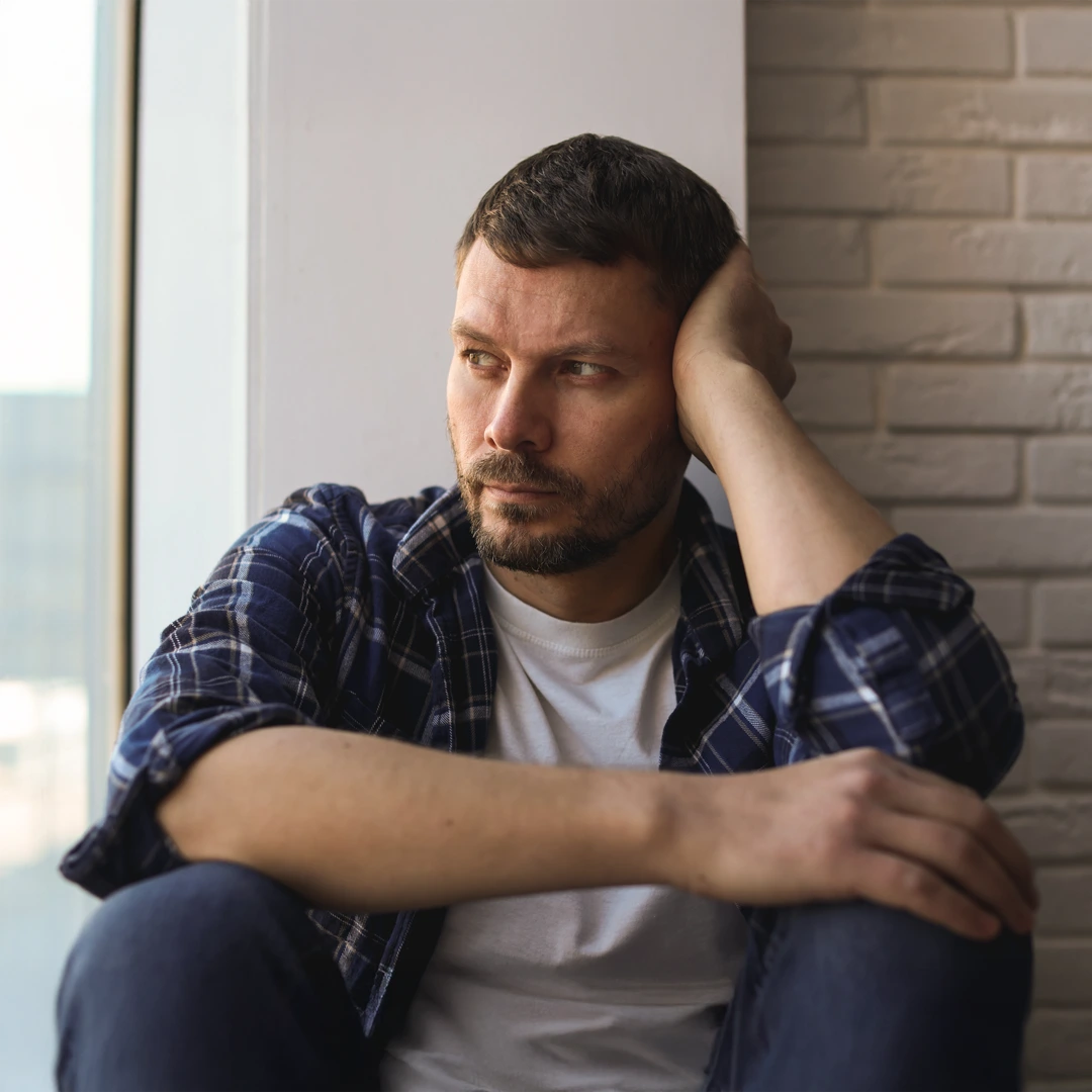 Our-Alcohol-Treatment-Services-at-Changes-Healing-Center-Mobile Thoughtful man sitting against a brick wall, reflecting on the challenges of alcohol addiction, symbolizing the need for compassionate rehab treatment in Phoenix.