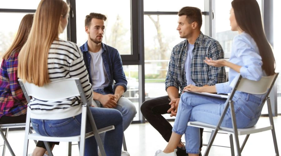 Group  sitting in a circle discussing topics for an AA Meeting that make a difference