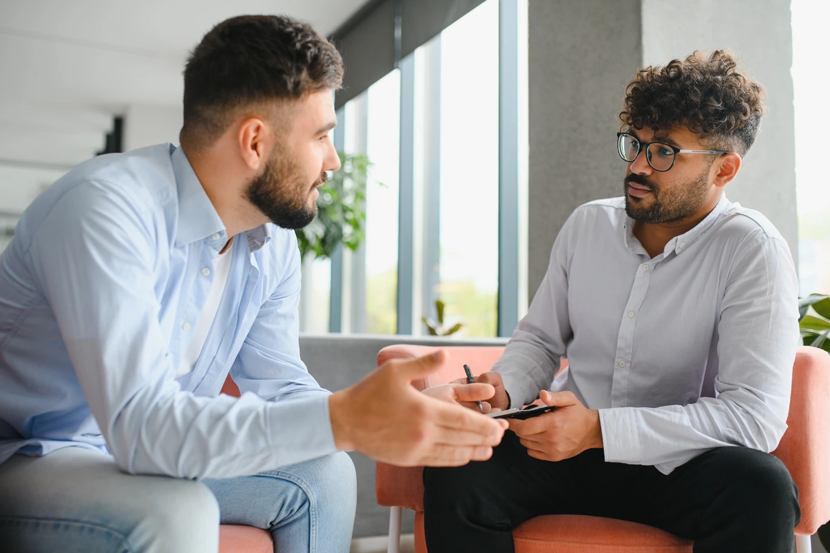 Mental-Health-Services-At-Changes-Healing-Center Two people sitting across from each other in a comfortable, softly lit therapy room, engaged in a counseling session.