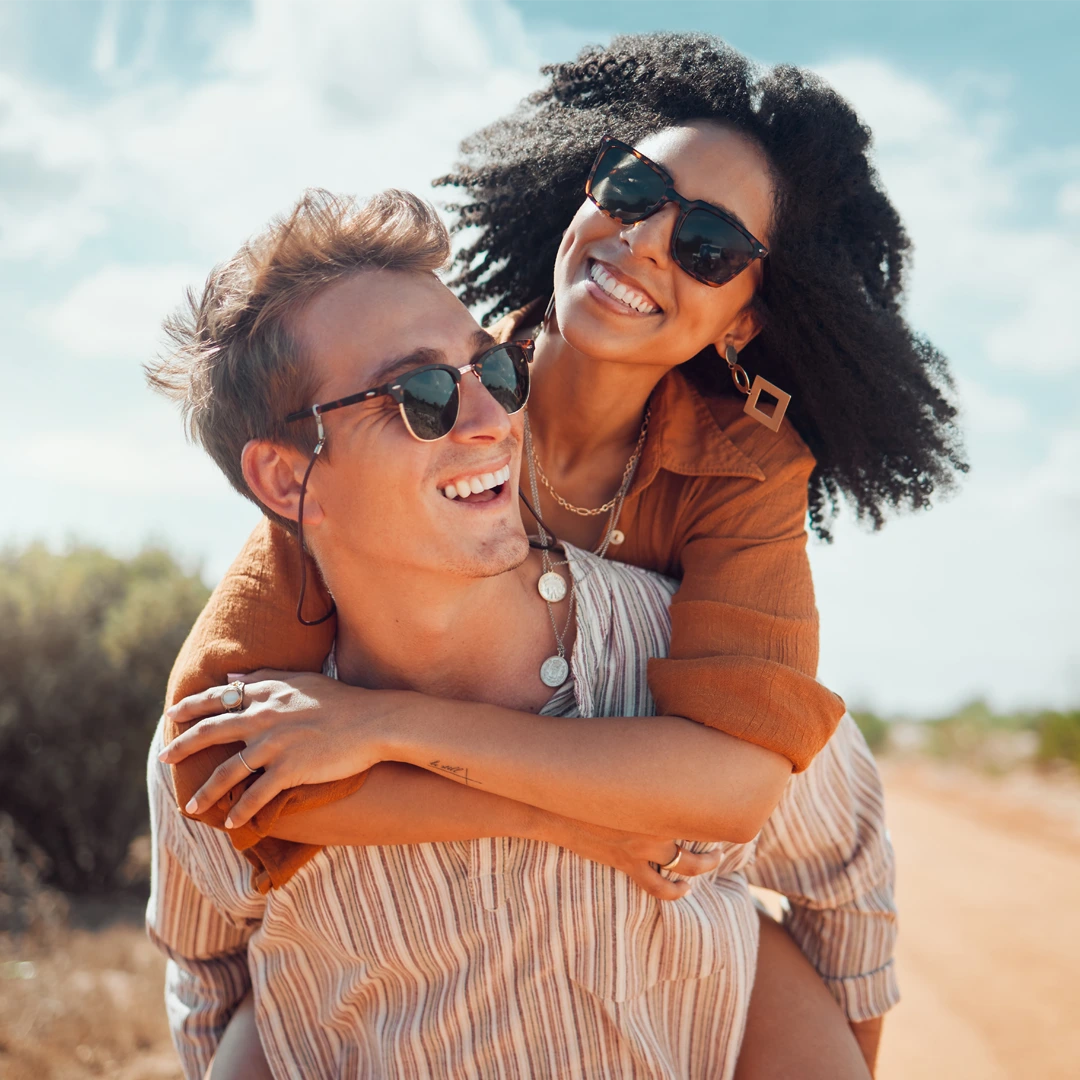 Smiling pair on a sunny desert trail—piggyback and sunglasses—capturing hope and connection in recovery near Mesa, AZ.