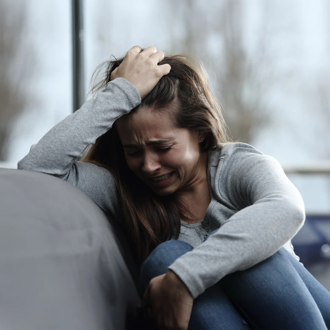 A-Closer-Look-at-Alcohol-Addiction-Treatment-Mobile Crying woman leaning against a couch, overwhelmed by the struggles of alcohol addiction, representing the urgent need for supportive rehab treatment in Phoenix.