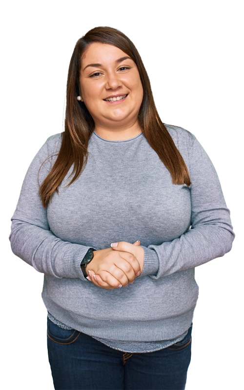 Smiling young woman in a gray sweater standing with hands clasped, symbolizing hope and support during meth addiction recovery.